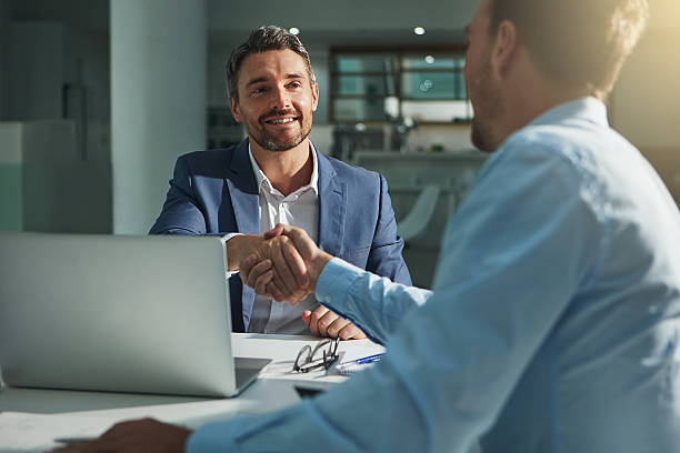 Two men in business attire shaking hands in an office, illustrating a successful banking partnership in the UAE.