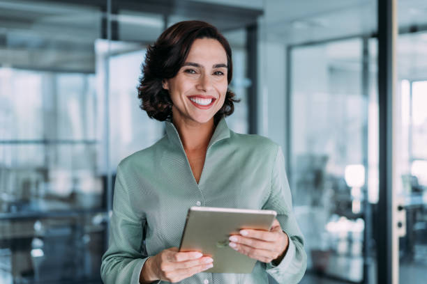 A smiling professional woman holding a tablet in a modern office, reflecting trust in UAE banking services.