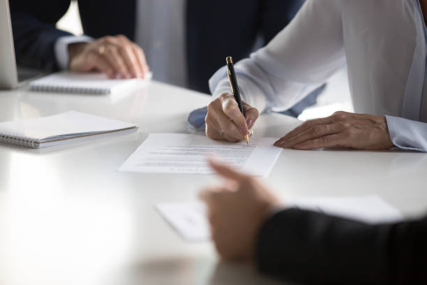 People signing documents at a meeting, discussing the best banks to open an account within the UAE.